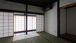 A traditional Japanese room with tatami flooring, sliding shoji doors, and a dark ceiling beam. - Solii (Ishikari)
