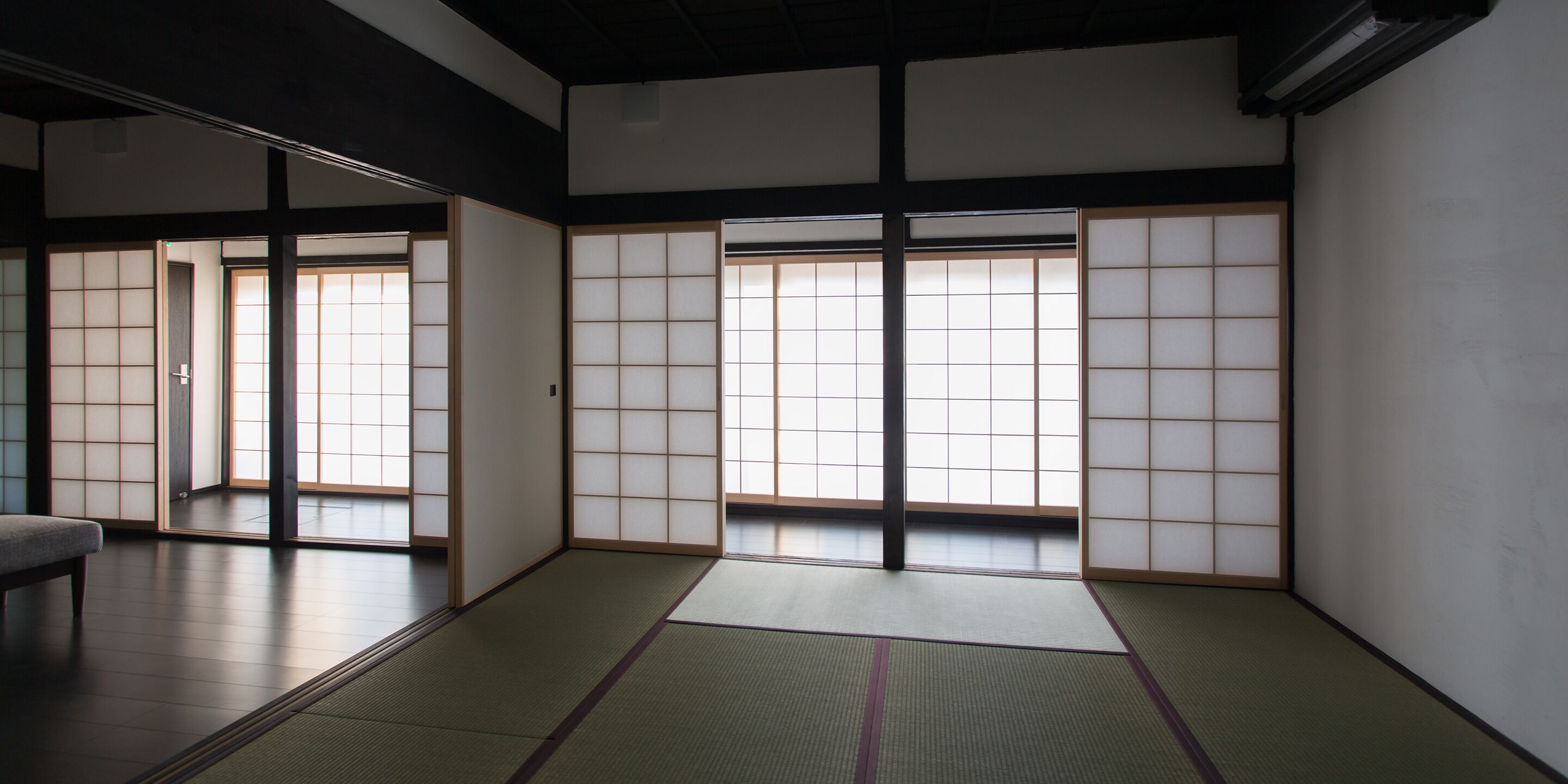 A traditional Japanese room with tatami flooring, sliding shoji doors, and a low ceiling.