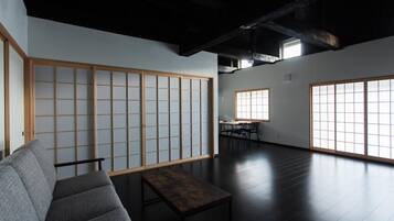 A modern interior with a tatami mat wall, a sofa, a table, and large windows.