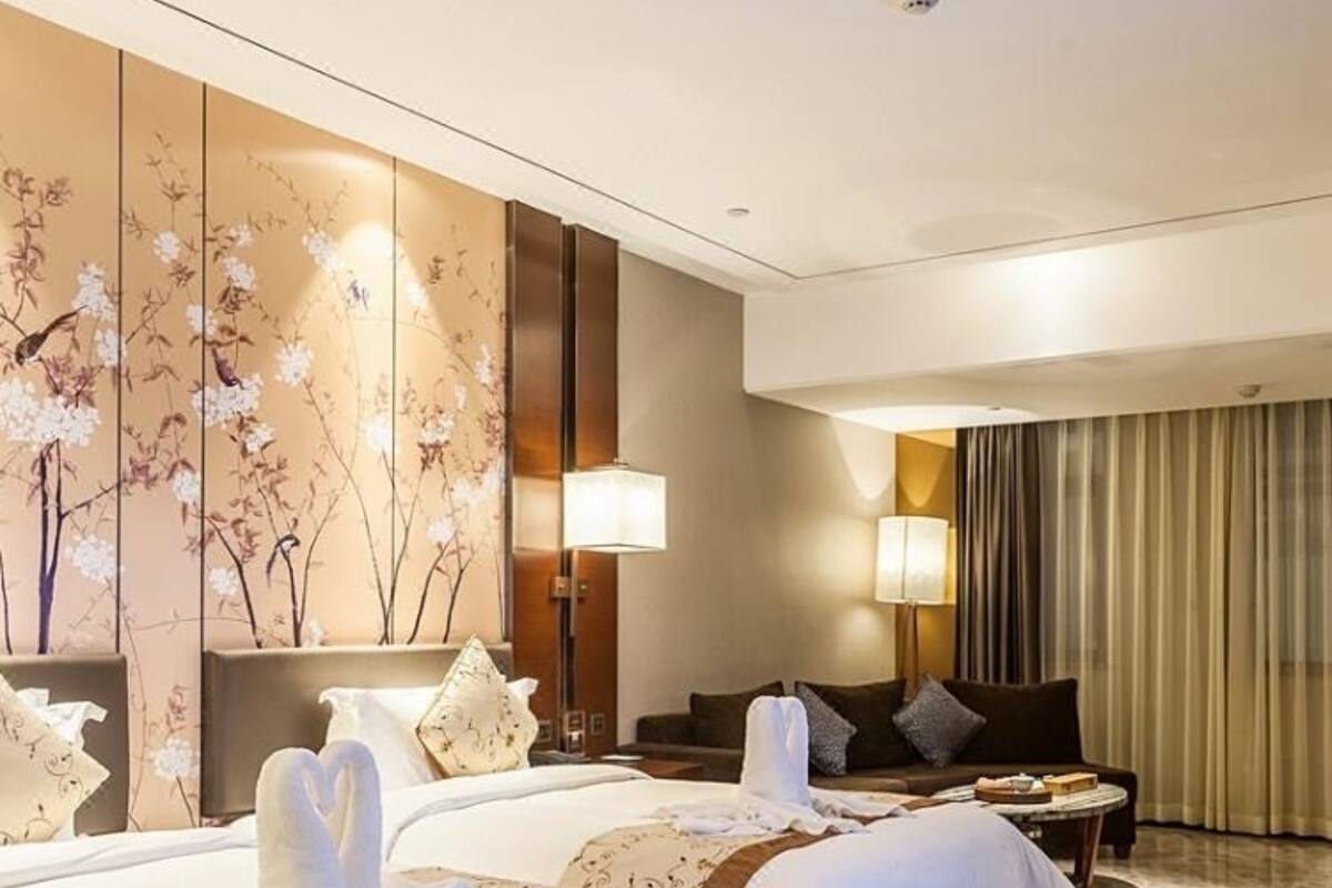 Habitación de hotel con dos camas, un sofá y una mesita.