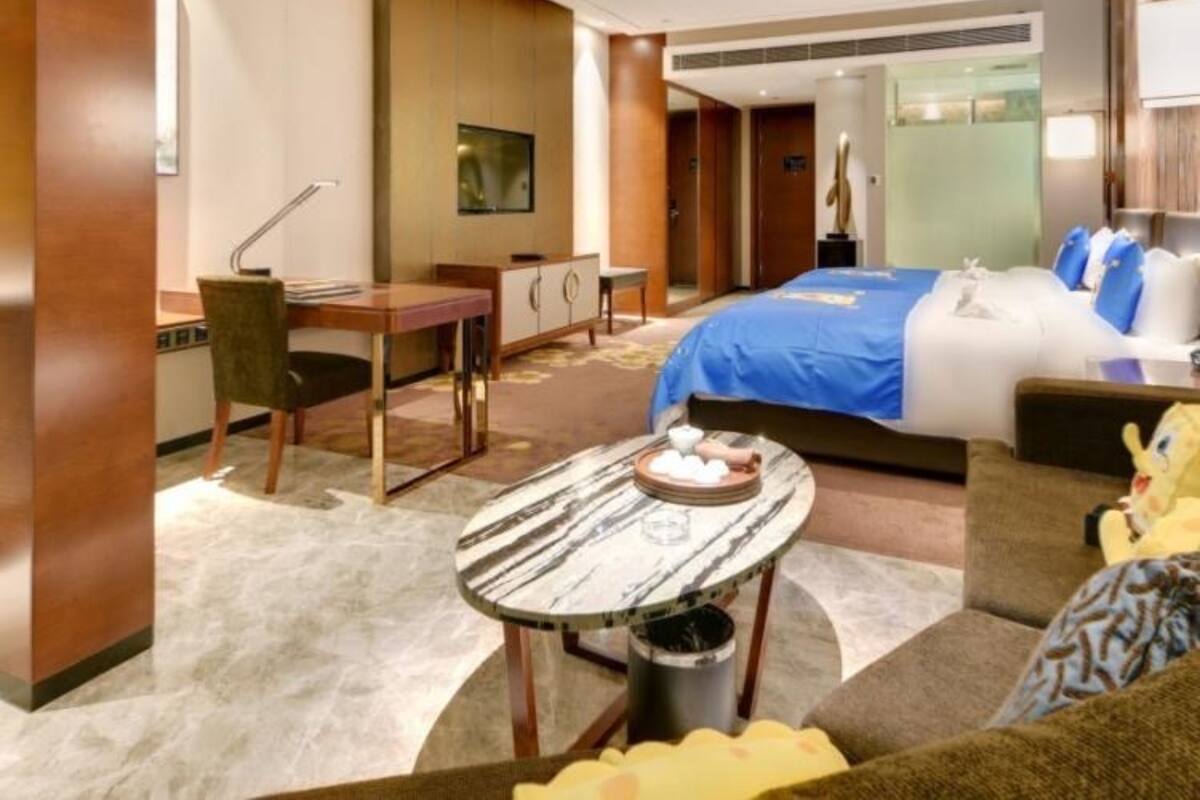 Una habitación de hotel con una cama, un escritorio, una silla, una mesita y un sofá.