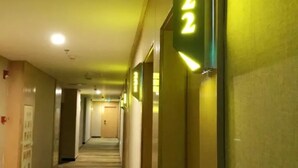 Un couloir d'hôtel avec un sol recouvert de moquette et des portes sur le côté droit.