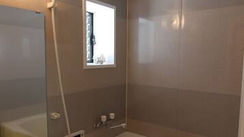 Une salle de bain avec une baignoire, un lavabo, un miroir et une fenêtre.