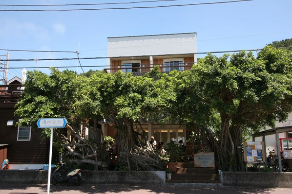 A building with a modern design, surrounded by lush greenery and a clear blue sky.