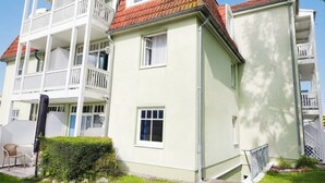 Een meerhoog woongebouw met balkons, een tuin en een pad naar de ingang.