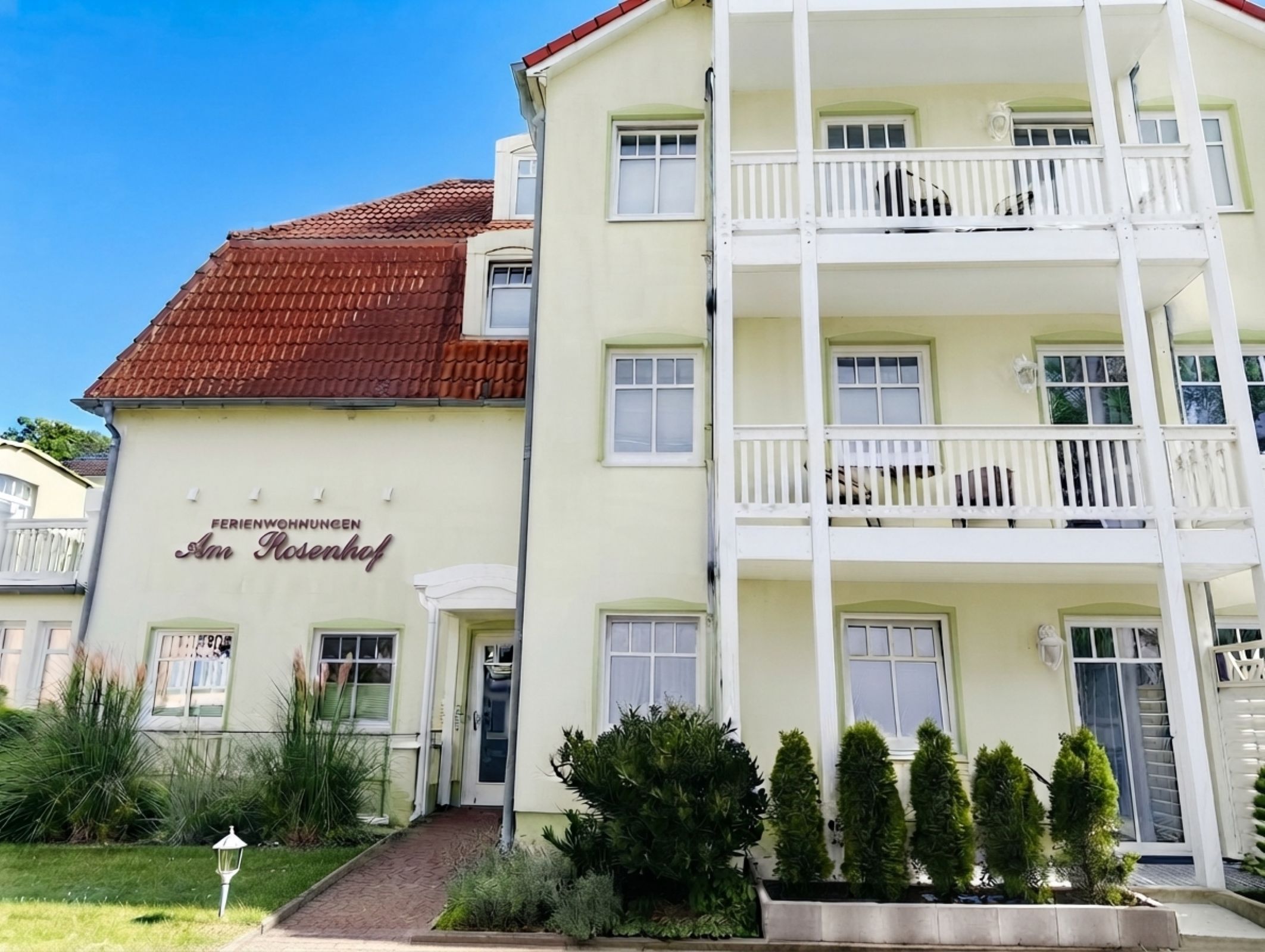 A multi-story hotel with a red-tiled roof, balconies, and a sign reading 'Ferienwohnungen Am Rosenhof'.