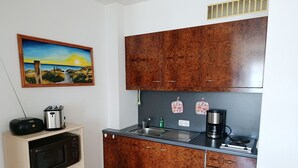 A compact kitchen with wooden cabinets, a microwave, a toaster, and a coffee maker.