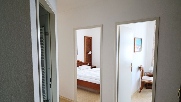 A hotel room with a bed, a nightstand, a chair, and a painting on the wall.
