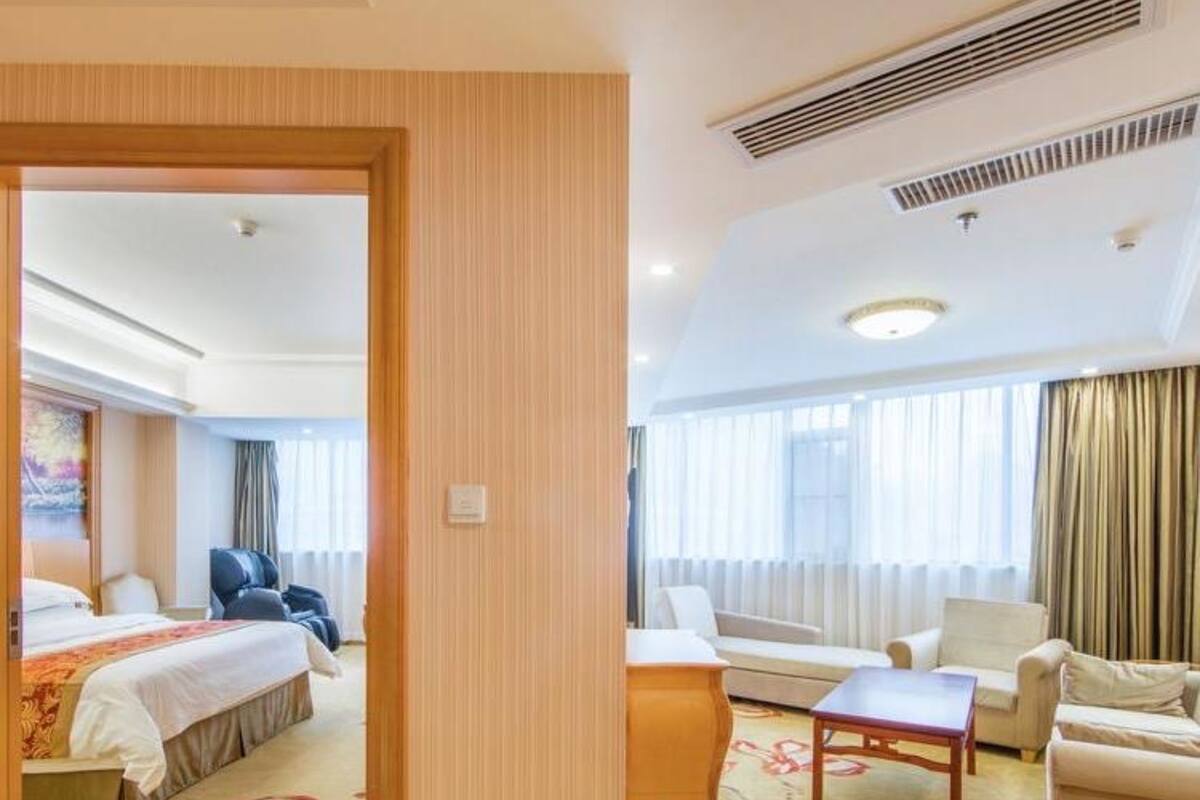 A hotel room with a bed, a desk, a chair, and a sofa.