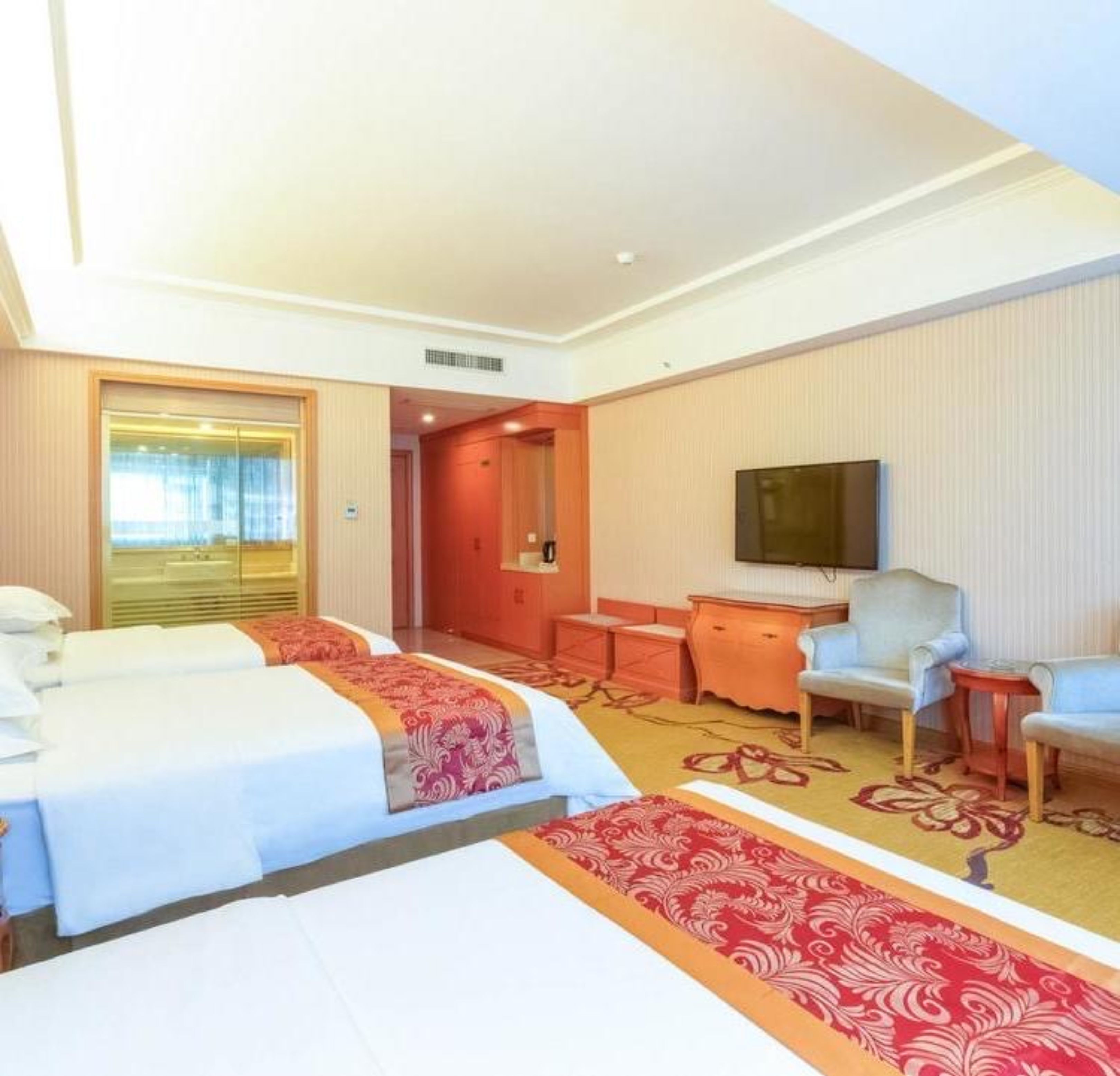 Ett hotellrum med två sängar, ett skrivbord, en stol, en TV och ett fönster.