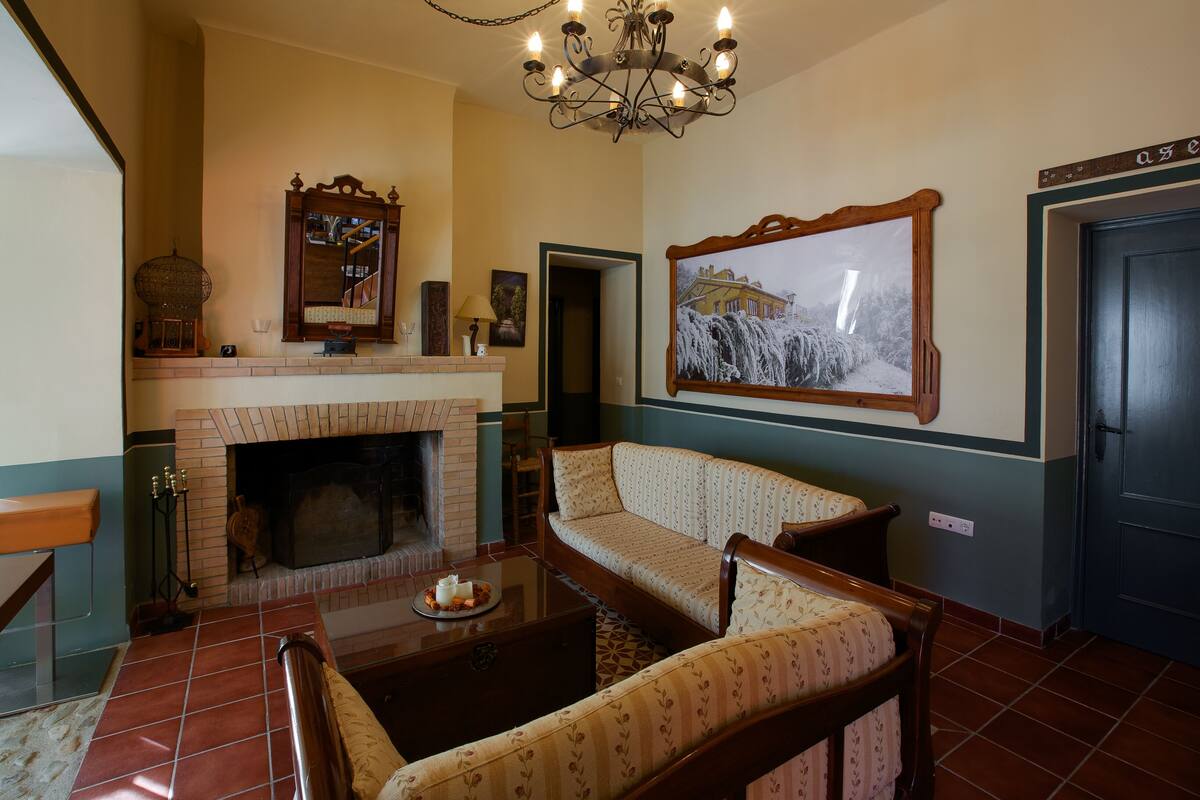 A cozy living room with a fireplace, a sofa, a coffee table, and a chandelier.