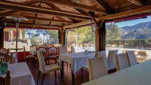 Zona de dinar a l'interior amb bigues de fusta, taules amb tovallons blancs i cadires.