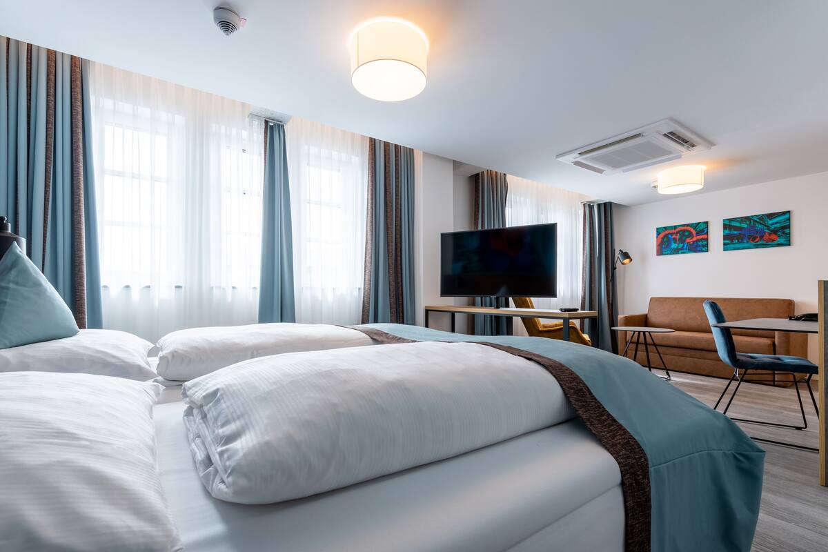 Une chambre d’hôtel avec un lit, une télévision, un bureau et un canapé.