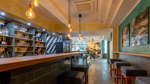 A bar area with shelves of bottles and glasses, wooden bar counter, and stools. - Trip Inn Living & Suites (Essen)