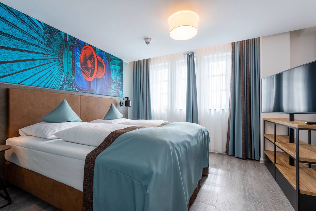 Une chambre d’hôtel avec un grand lit, une télévision et un tableau au mur.