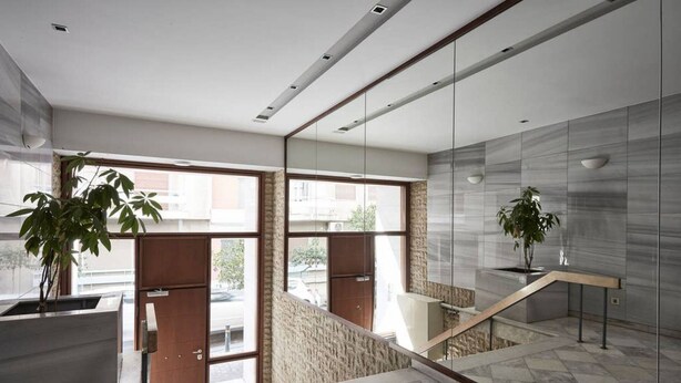 A modern interior with a staircase, large windows, and potted plants. - Modern Elegant Apartment at Kolonaki (Athina)