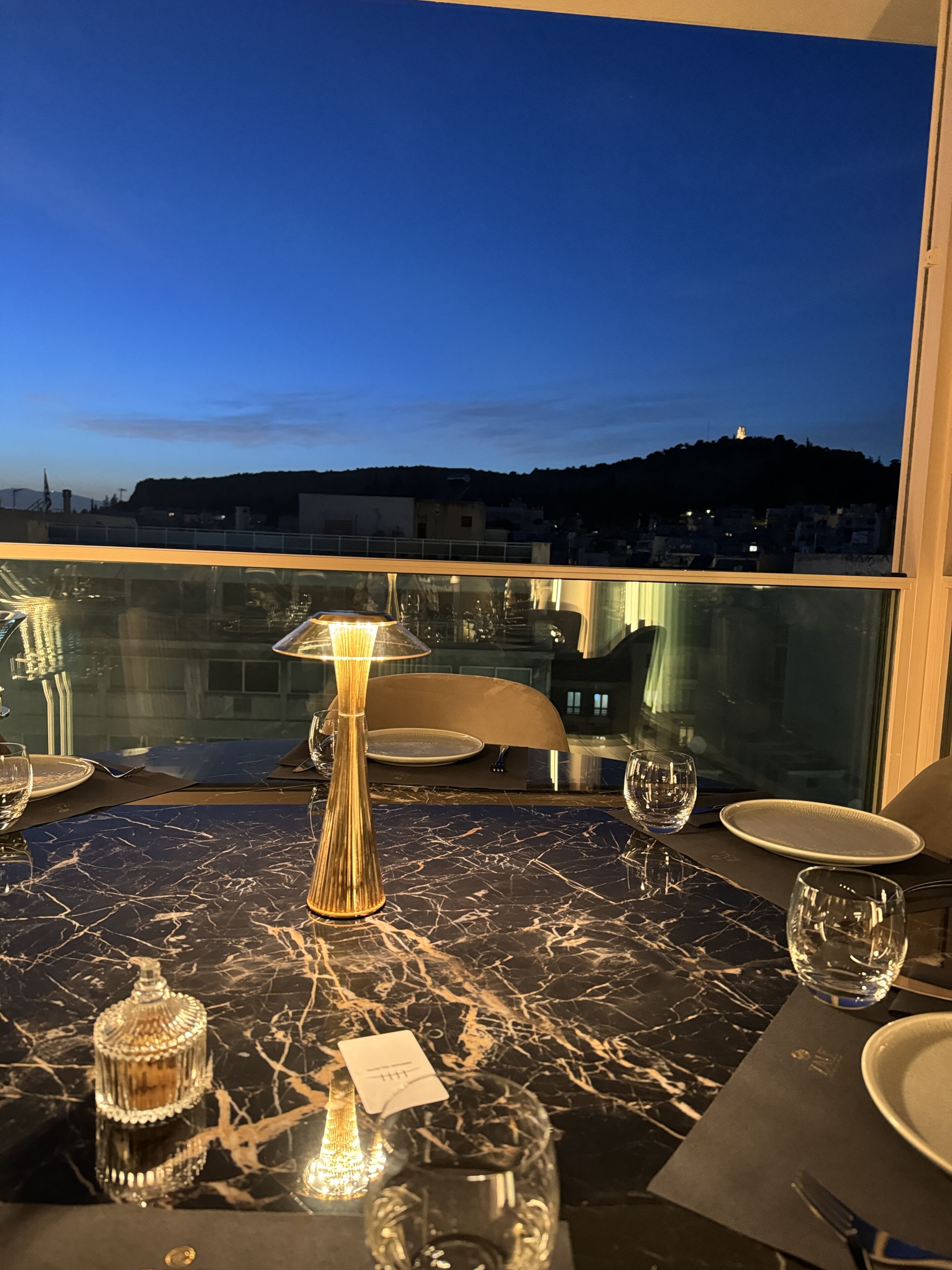 A dining table with a view of a cityscape at dusk.
