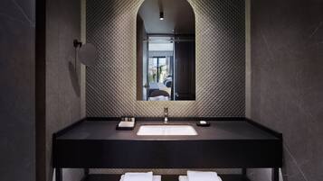 A modern bathroom with a black countertop, a large mirror, and a built-in sink. There are two white towels on the countertop.