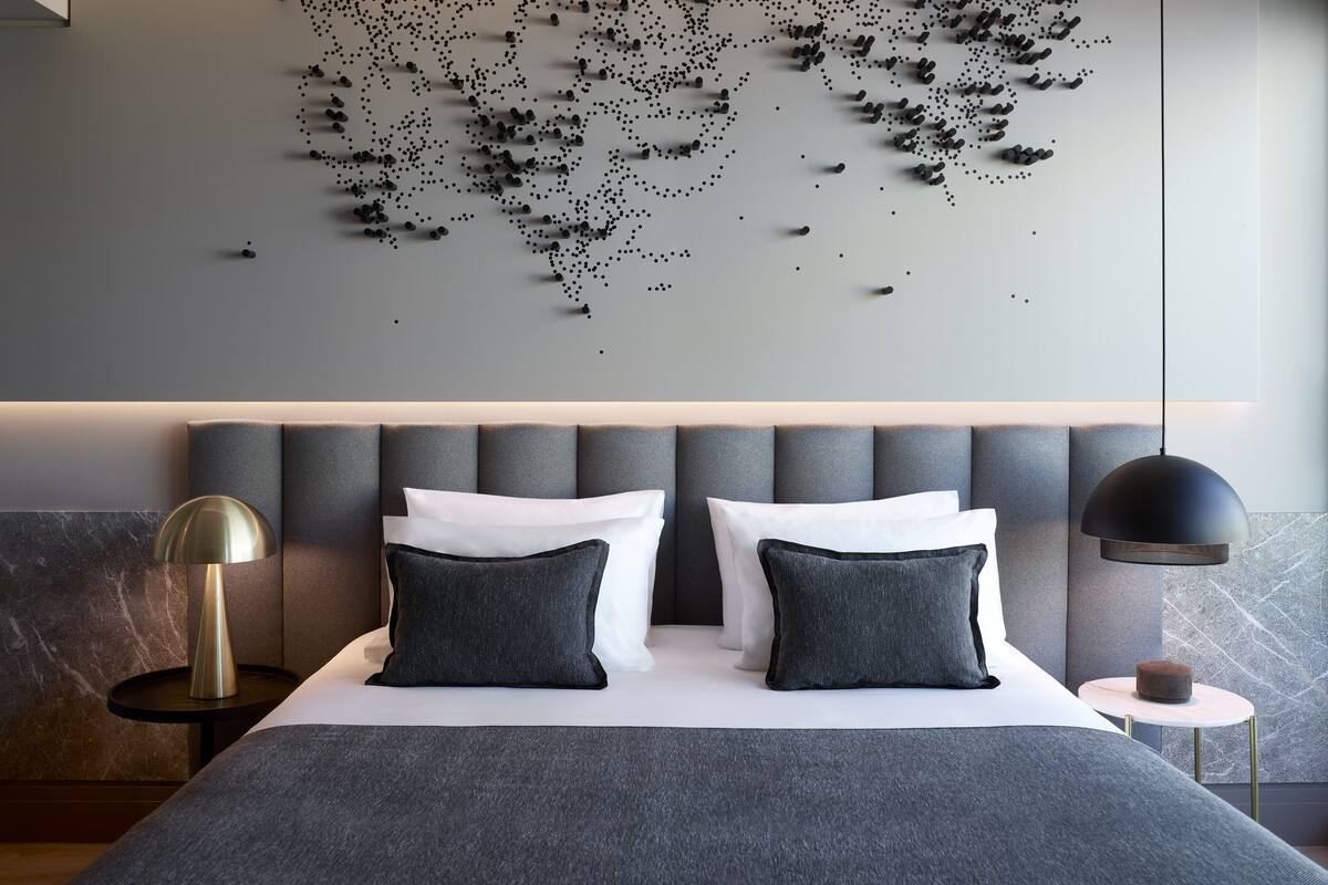 A modern bedroom with a large bed, grey upholstered headboard, and a world map wall art.