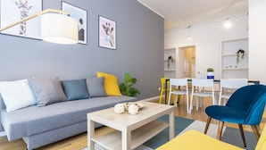 A modern living room with a grey sofa, yellow cushions, a wooden coffee table, and a blue chair. - Santa Valeria - 4 Bedrooms Apartment (Milan)