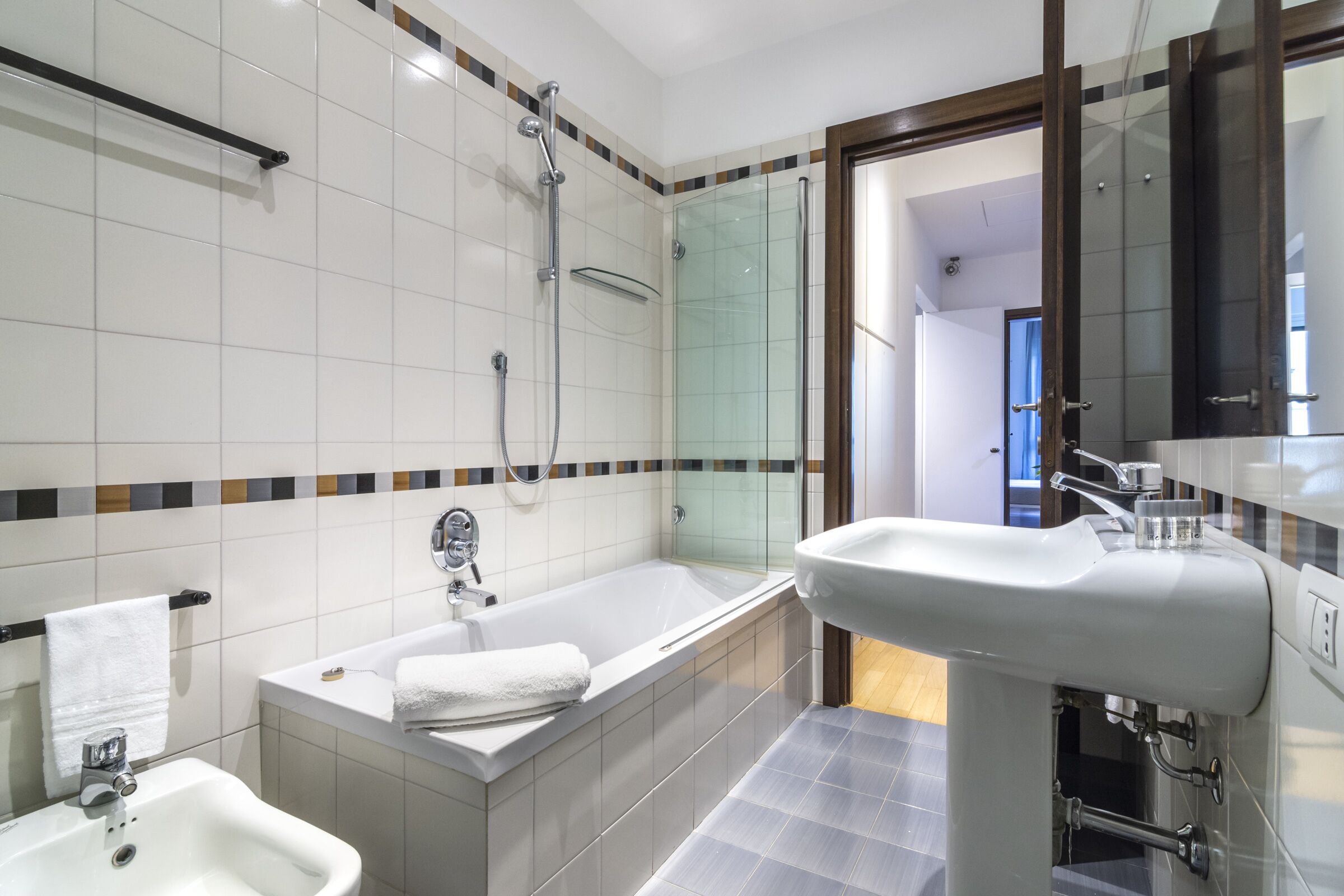 Un baño moderno con bañera, lavamanos y ducha con mampara de vidrio.