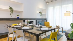 A modern dining area with a wooden table set for four, surrounded by white and yellow chairs. - Santa Valeria - 4 Bedrooms Apartment (Milan)