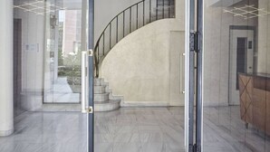 A modern interior with a curved staircase, glass doors, and a minimalist design. - Chic One Bedroom Apartment with Hilton View (Athens)