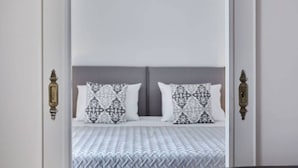 A bedroom with a bed, two patterned pillows, and a white headboard. - Chic One Bedroom Apartment with Hilton View (Athens)