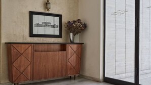A reception area with a wooden console, a framed cityscape picture, and a vase with dried flowers. - Chic One Bedroom Apartment with Hilton View (Athens)