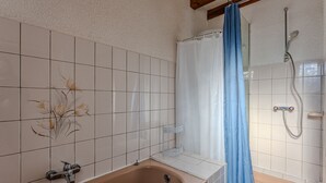 A bathroom with a bathtub, shower, and tiled walls. - Charming 2-BR House with Terrace, Near Beach & Town Center, Sleeps 6 (Biscarrosse Plage)