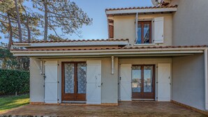 A two-story house with a tiled roof, a front porch, and a small garden area. - Charming 2-BR House with Terrace, Near Beach & Town Center, Sleeps 6 (Biscarrosse Plage)