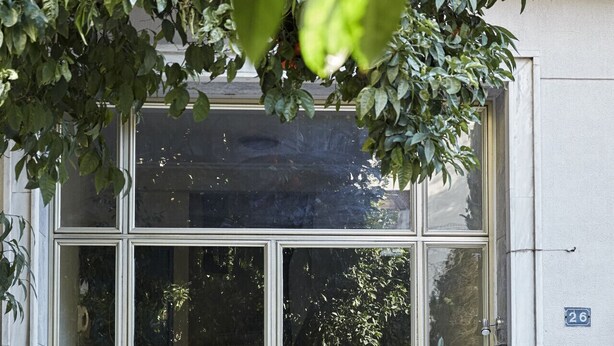 A building entrance with large glass doors, a visible number '26' sign, and a car parked in front. - Charming 1bd Apt next to Concert Hall (Athina)
