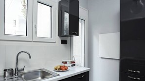A modern kitchen with a stainless steel sink, black cabinets, and a window above the sink. - Charming 1bd Apt next to Concert Hall (Athina)