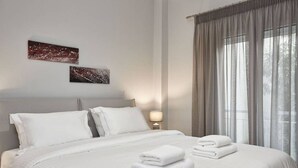 A hotel room with a large bed, two pillows, a nightstand with a lamp, and two wall art pieces. - Charming 1bd Apt next to Concert Hall (Athina)