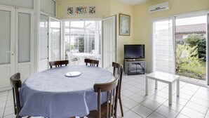 A dining area with a round table, chairs, and a television.