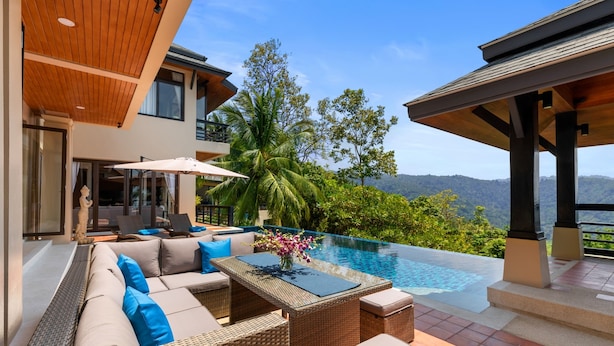 A modern outdoor lounge area with a pool, wicker furniture, and a view of the mountains. - Vista Mar (Koh Samui)