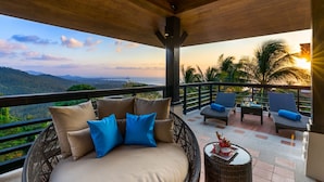 A balcony with a wicker sofa, two lounge chairs, and a small table. - Vista Mar (Koh Samui)