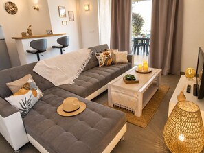 A modern living room with a grey sectional sofa, a white coffee table, and a TV stand.