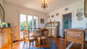 A spacious kitchen with a dining area, featuring a wooden table, chairs, and a chandelier. - Villa Tramonto facing the seashore (Portoferraio)