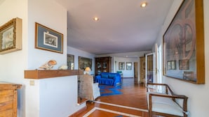 A spacious living area with a blue sofa, wooden furniture, and artwork on the walls. - Villa Tramonto facing the seashore (Portoferraio)