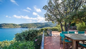 A patio with a table and chairs overlooking a coastal landscape. - Villa Tramonto facing the seashore (Portoferraio)