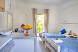 A hotel room with two beds, a desk with a computer, a scale, and a fruit bowl. - La Casa De Dalia (Corfu)