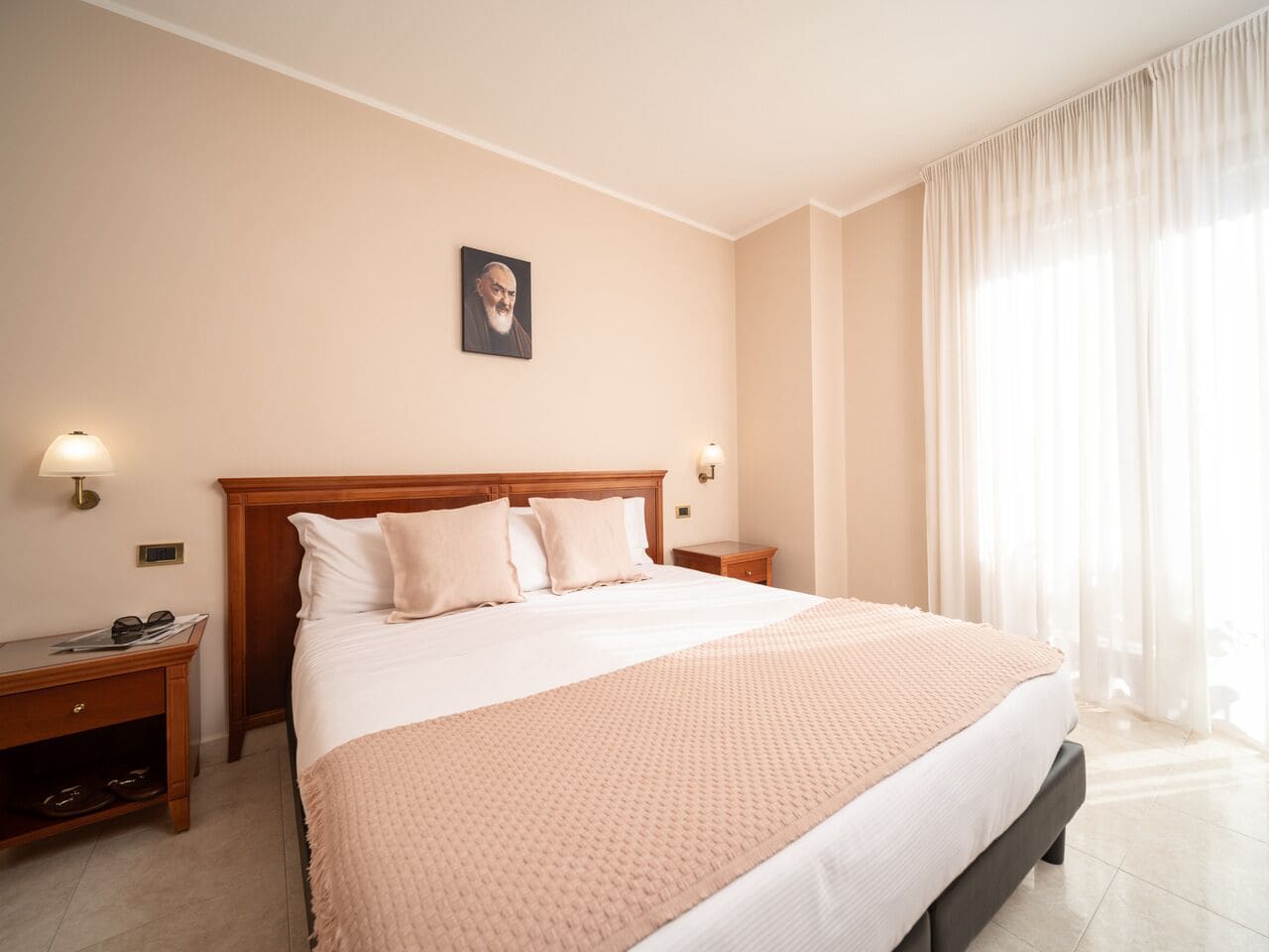 A neatly made bed with a wooden headboard, a bedside table with a lamp, and a picture on the wall.