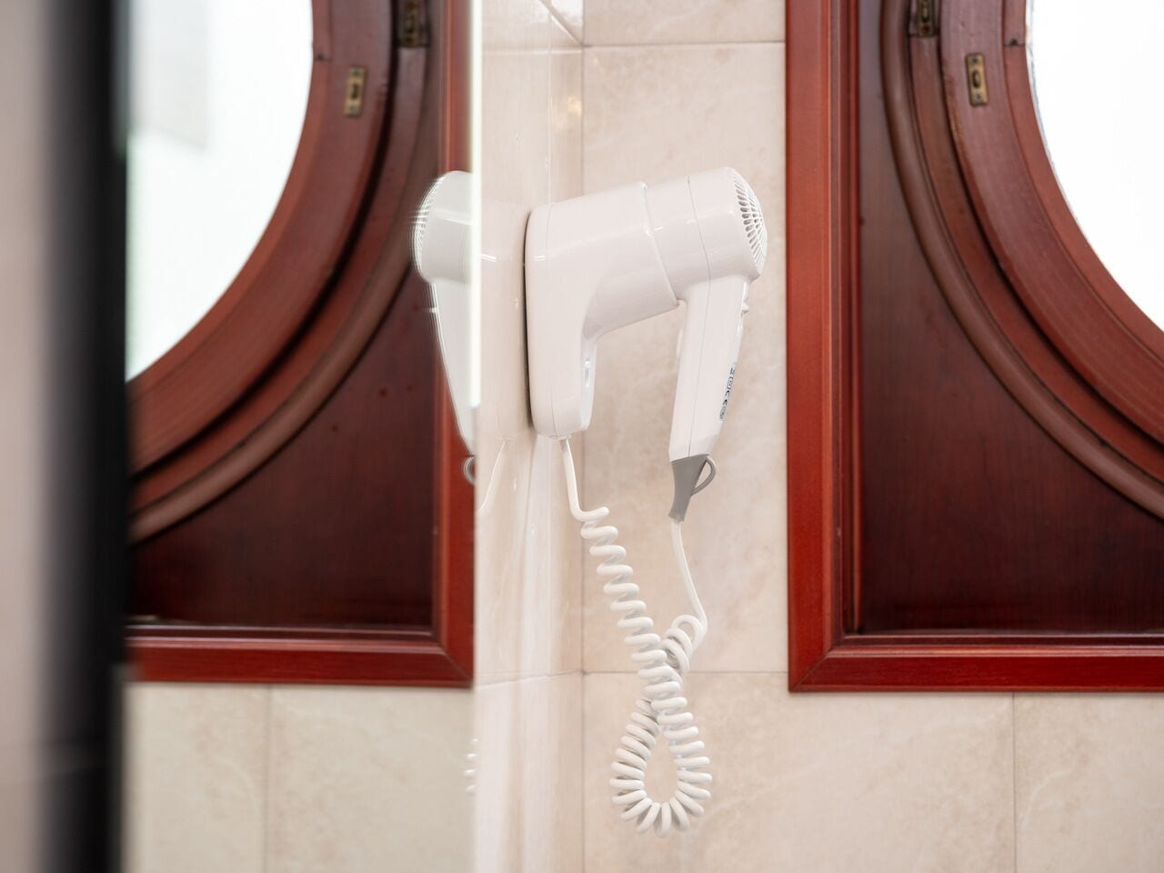 Ein an der Wand befestigter Haartrockner mit aufgewickeltem Kabel.