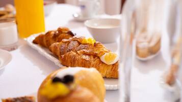 Mesa com croissants, garrafa de sumo de laranja e copo de leite.