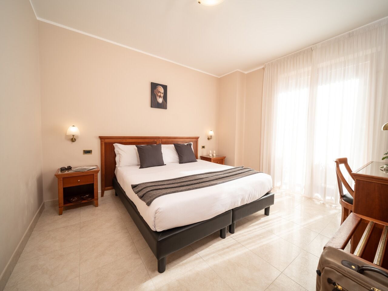 A hotel room with a large bed, bedside tables, a desk, and a chair.