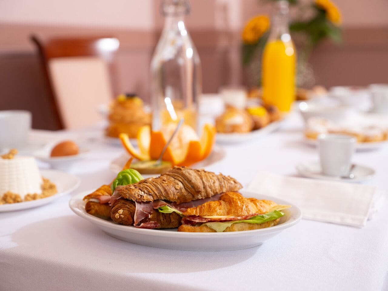 Una colazione con croissant, spicchi d'arancia e una bottiglia di succo d'arancia su un tavolo.