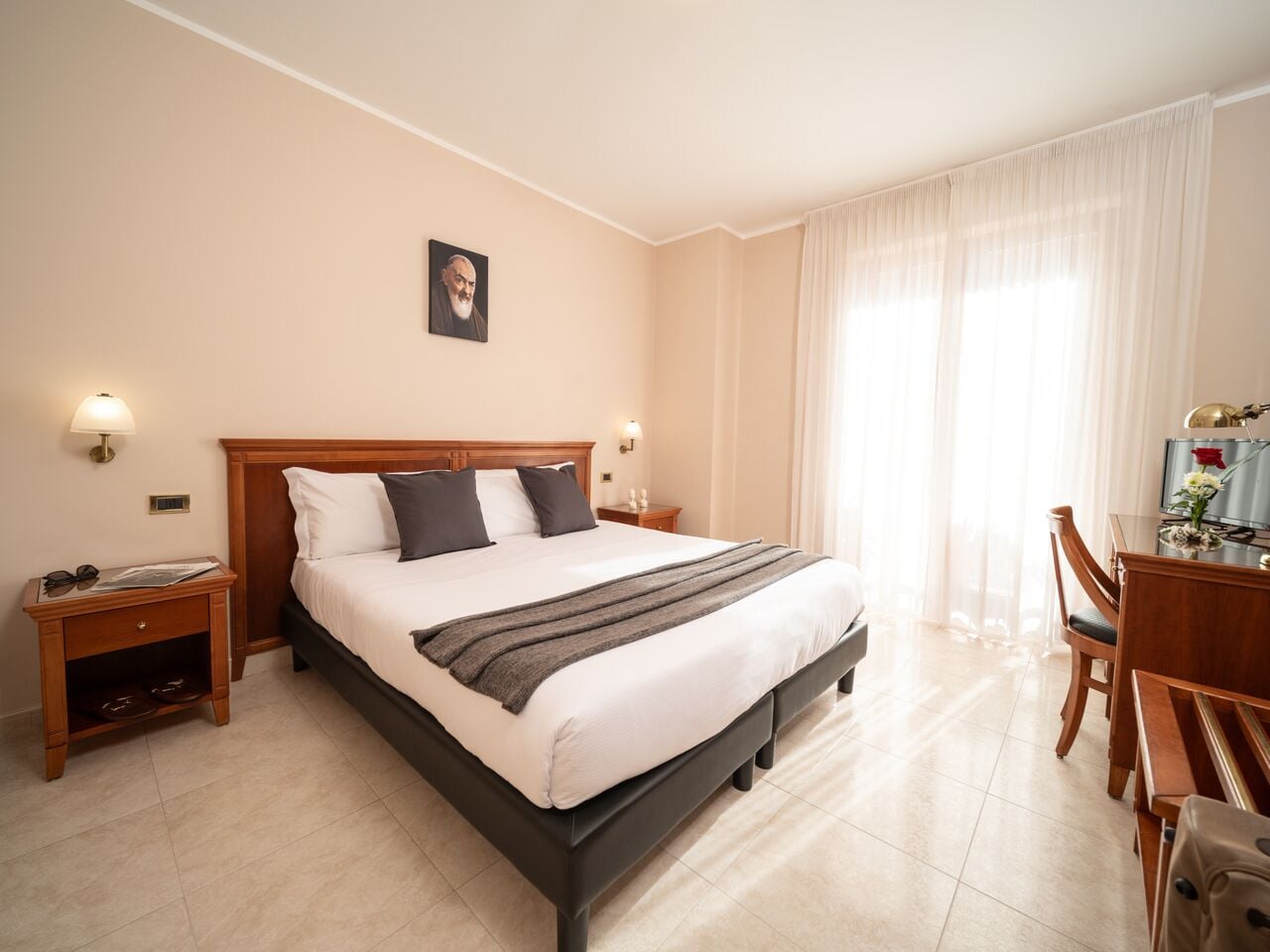 Une chambre d’hôtel avec un grand lit, des tables de chevet, un bureau et une chaise.
