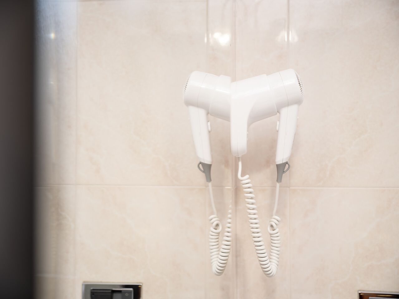 A hair dryer mounted on a wall in a bathroom.