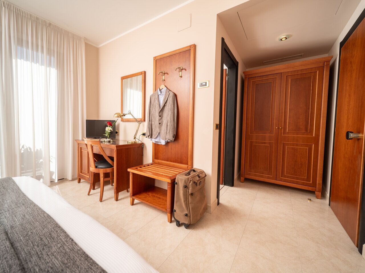Een hotelkamer met een bed, bureau, stoel en een kledingkast.